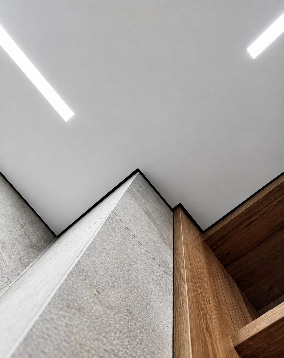 Two ceiling light lines meeting at a sharp architectural apex