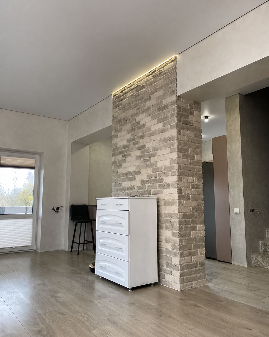 A shadow-gap ceiling meeting an exposed brick column