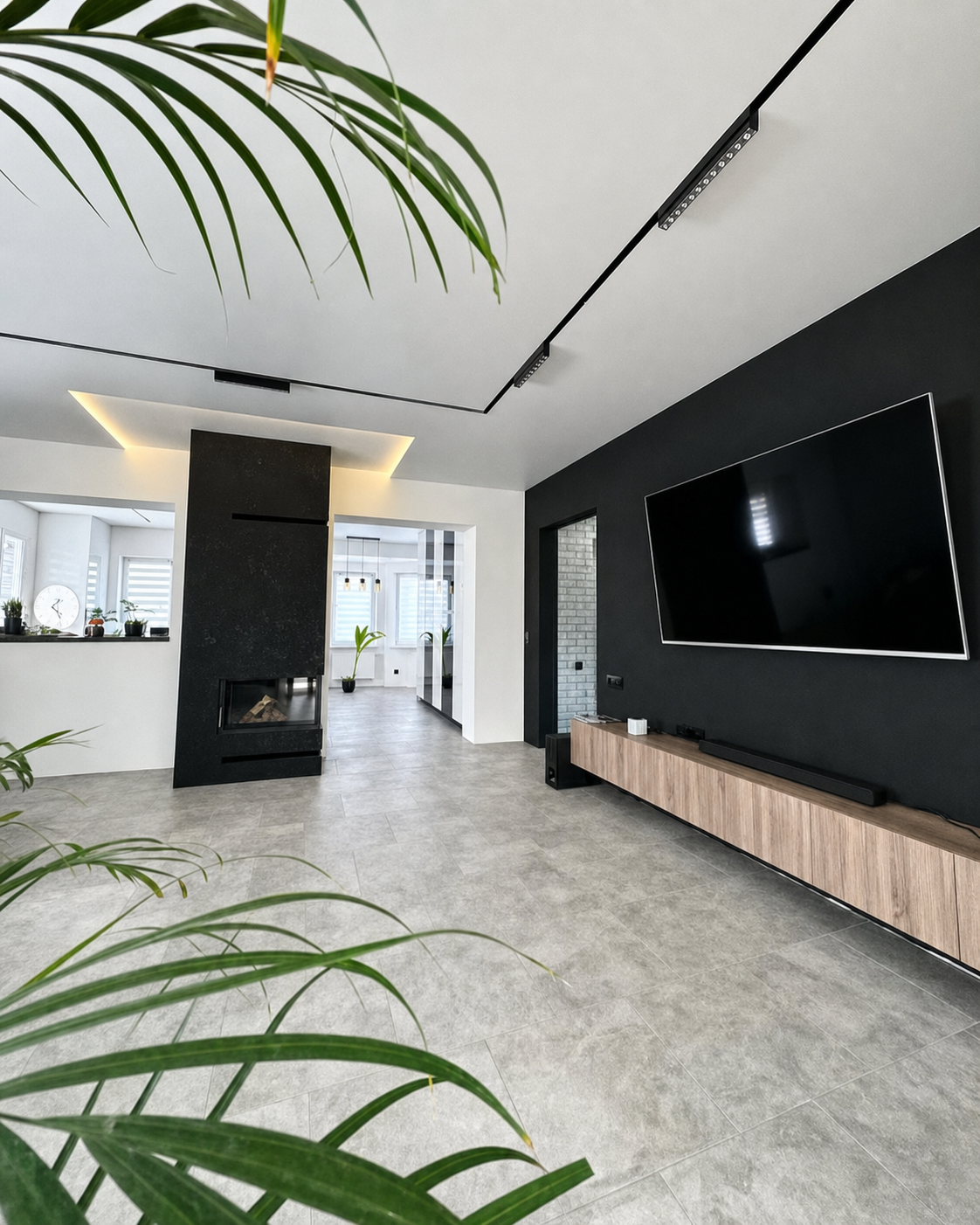 A backlit ceiling reveal meeting a raw stone chimney breast